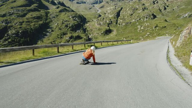 Cinematic downhill longboard session. Young woman skateboarding and making tricks between the curves on a mountain pass. Concept about extreme sports and people