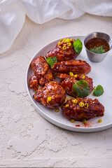 Frying wings in a sauce with onions, sauce in a bowl and nasturtia leaves
