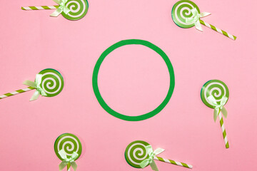 lollipops around green circle on pink background, copy space, creative art modern design
