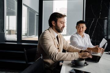 Two midaged businessmen working with laptop and clipboard with documents