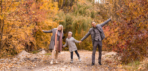 Young happy family while walking in the autumn park.