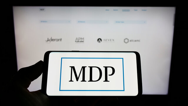 Stuttgart, Germany - 07-16-2022: Person holding cellphone with logo of American company Madison Dearborn Partners LLC (MDP) on screen in front of webpage. Focus on phone display.