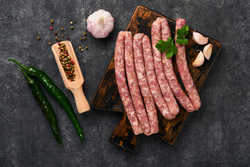 Raw sausages. Bratwurst or sausages with ingredients on cutting board with spices on a stone...
