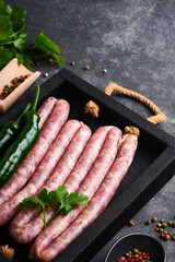 Raw sausages. Bratwurst or sausages with ingredients on cutting board with spices on a stone...