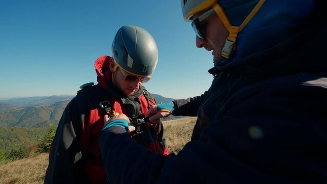 Man helping paragliding pilot to prepare for flight.