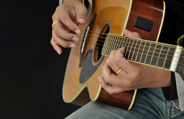 guitarist playing acoustic guitar on black background, selective focus