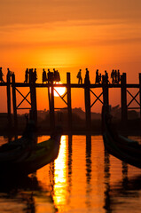 The people of Myanmar crossing U Bein Bridge at Sunset.