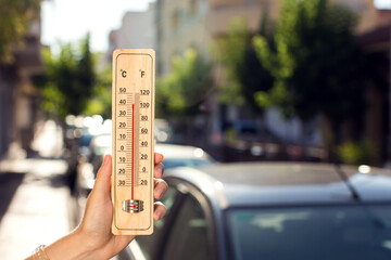Hot weather. Thermometer in front of an urban scene during heatwave.