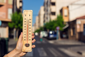 Hot weather. Thermometer in front of an urban scene during heatwave. - obrazy, fototapety, plakaty