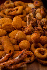 Cheese sticks in batter, fried shrimps, onion rings, cheese balls, deep-fried chicken legs