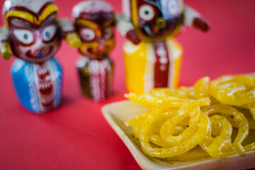 jalebi or jilipi served on plate in front of idols of lord jagannath, balaram and suvadra, during celebration of ratha yatra festival in india.