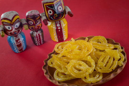 jalebi or jilipi served on plate in front of idols of lord jagannath, balaram and suvadra, during celebration of ratha yatra festival in india.