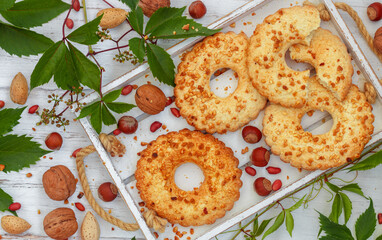 Homemade cookies. Cookies with nuts (hazelnuts, walnuts, almonds, peanuts) in the form of rings on a white wooden board on a light background. Culinary background. Selective focus, Top view, flatley
