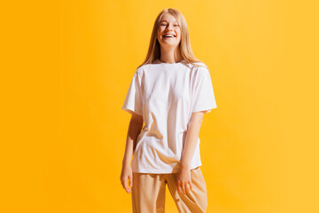 Cheerful young beautiful girl, student in casual style outfit isolated on bright yellow background. Concept of beauty, art, fashion, human emotions