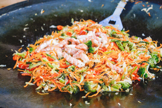 Cooking A Warm Carrot, Broccoli, Mussel, Shrimp, Sweet Pepper And Cabbage Salad In A Pan At A Street Food Festival