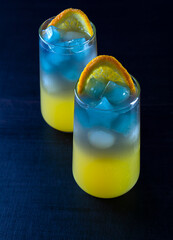 Non-alcoholic cocktail made from orange juice and blue Thai tea. Cubes in the form of stars. Summer refreshing drink. High quality photo