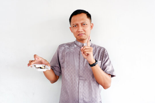 Asian man brings an ashtray with his right hand and gives a no smoking code isolated on white background.