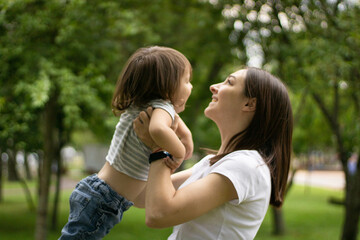 Fototapeta premium Mom throws baby in air,playing in park.
