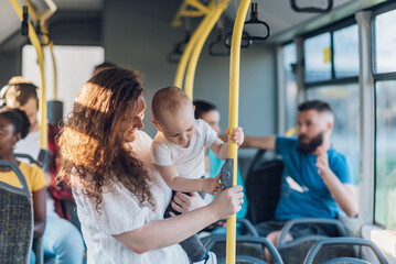 Mother holding her baby boy and riding a bus in the city