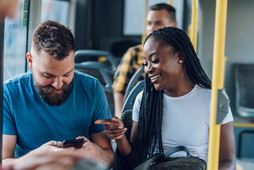 Multiracial friends talking while riding a bus in the city and using a smartphone © Zamrznuti tonovi