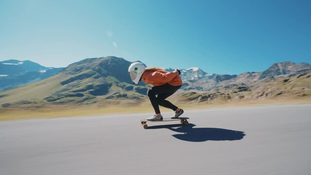 Cinematic downhill longboard session. Young woman skateboarding and making tricks between the curves on a mountain pass. Concept about extreme sports and people