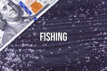 FISHING - word (text) on a dark wooden background, money, dollars and snow. Business concept (copy space).