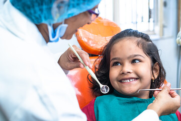 happy smiling kid looking at dentist while treating at hospital - concept of dental care, expertise...