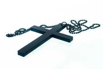 Black christian cross necklace isolated on white background.