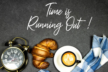 Time is Running Out Concept, Fresh baked croissants on black board for breakfast and coffee cup with leaf late art and alarm clock showing seven o'clock on gray grunge background