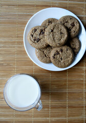 A glass glass with milk on a wooden mat with oatmeal cookies. Afternoon lunch with cookies. Sweet cookies with milk.