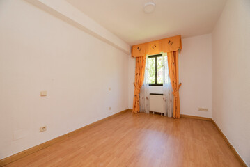 Empty room with oak hardwood floor, white painted walls and matching millwork and window with yellow curtains