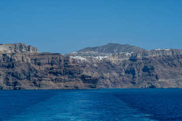 View of Santorini island and wave trails of a floating ferry boat