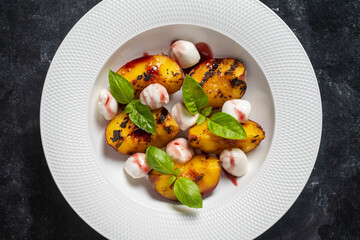 Grilled peach salad with mozzarella, green basil and sauce , close up, top view