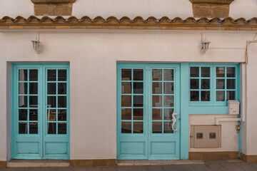 Exterior of a cafe building with teal blue doors and windows in Tossa de mar