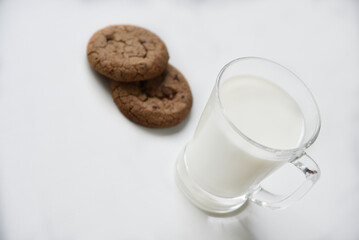 Glass glass with milk on a white background with oatmeal cookies. Afternoon lunch with cookies. Sweet cookies with milk.