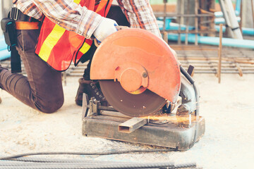 Young manual worker using grinder on metal in factory. Worker grinding in a workshop. Heavy industry factory, metalwork