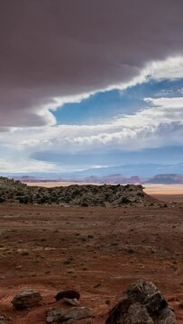 Looking over the red glowing desert during timelapse as clouds roll in the sky looking towards Capitol Reef in Utah.