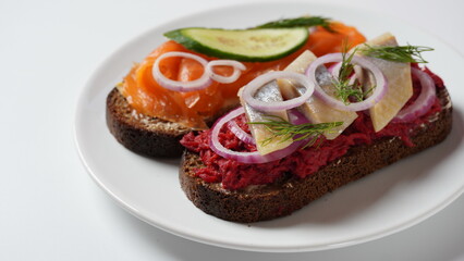 Danish open sandwich Smorrebrod on dark rye bread with herring, salmon, beetroot, red onions, and radish