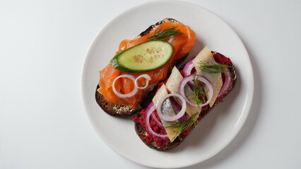 Danish open sandwich Smorrebrod on dark rye bread with herring, salmon, beetroot, red onions, and radish