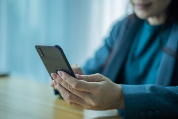 Senior asian woman using smartphone while sitting at home office.