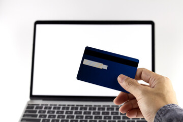 Young man hand holding credit card online shopping with white laptop background.