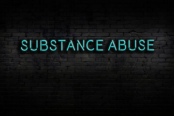 Neon sign. Word substance abuse against brick wall. Night view