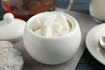 Refined sugar cubes in ceramic bowl on table