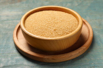 Brown sugar in bowl on light blue wooden table