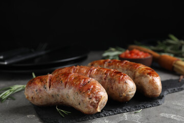 Tasty grilled sausages served on grey table