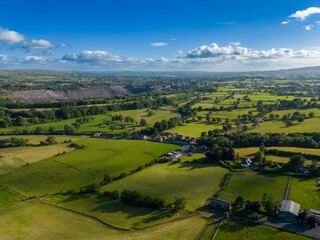 Bird's eye view of houses surrounded by green cultivated fields in a countryside