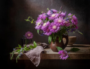 Still life with a bouquet of cornflowers in a clay jug on an old wooden table