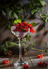 Redcurrant in a glass wine glass on a wooden table