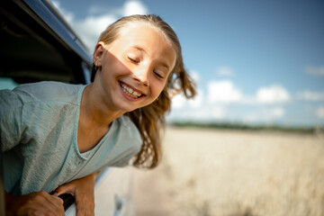 A five-year-old girl stuck her face out of the window of a moving car. Joyful emotions of a child