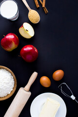 Top view of ingredients for making apple pie or cake on the black background. Copy space. Location vertical.